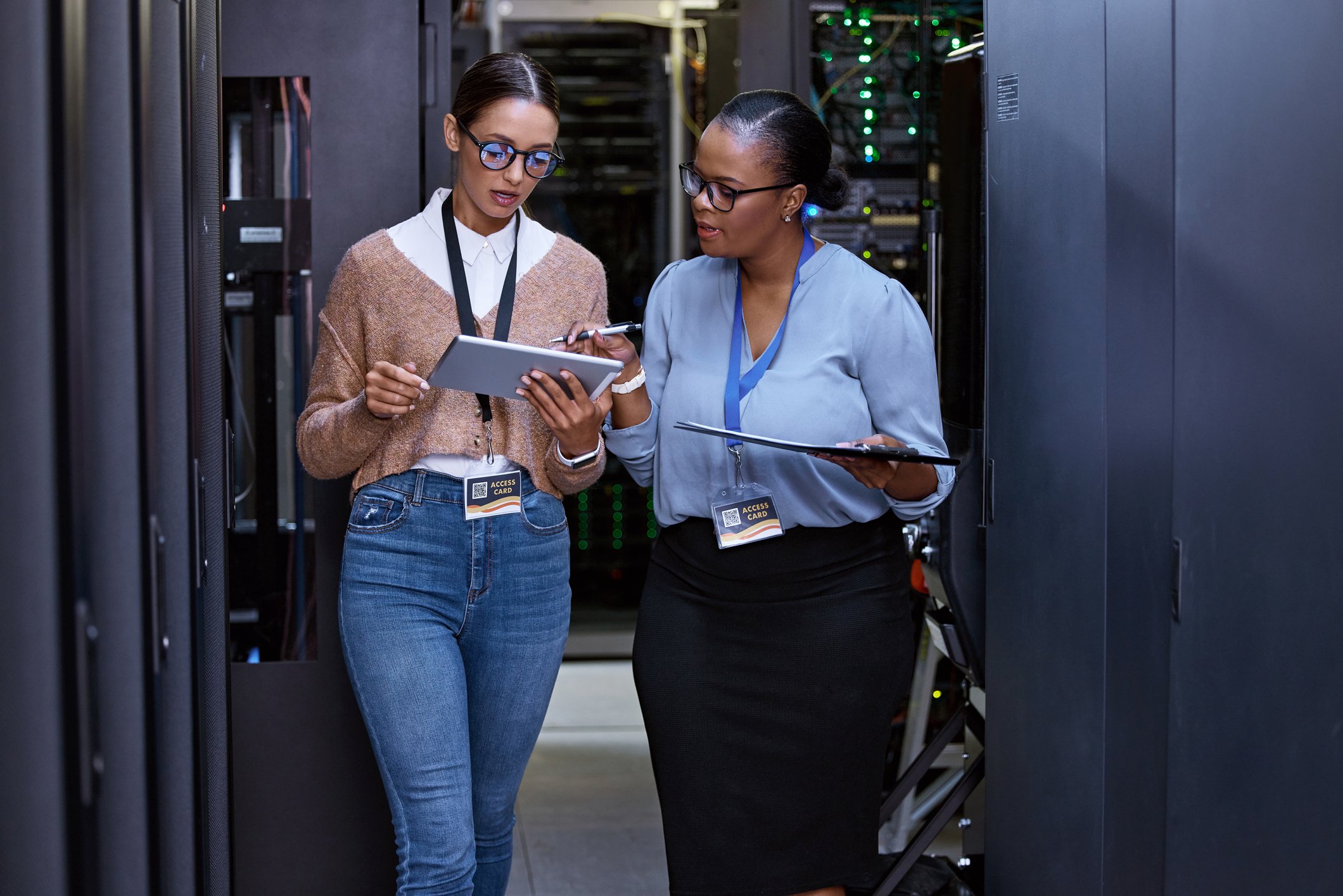 Two information technology specialists are in the IT room and looking at a computer